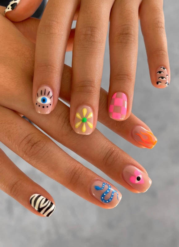 Fingers with colorful and unique nail art designs against a grey background. Spring Nail Ideas For 2024.