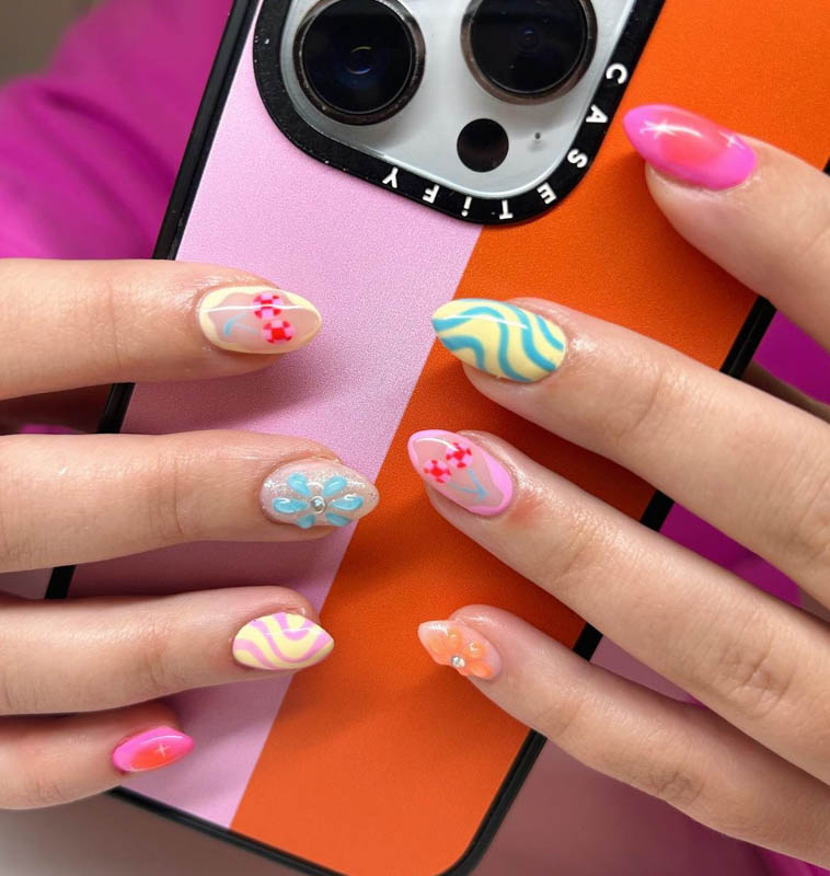 A close-up image of a hand with intricately designed nails, holding a smartphone with a dual-tone case that says CASETiFY. Spring Nail Ideas For 2024.