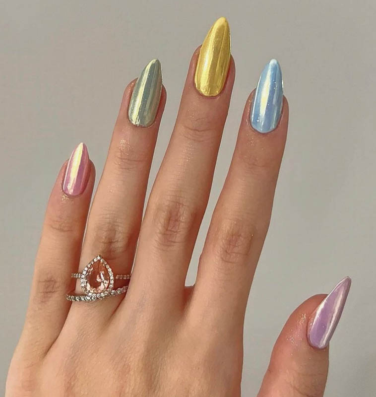 A hand displaying pearl colored nails and a teardrop-shaped ring with encrusted gems. Spring Nail Ideas For 2024.