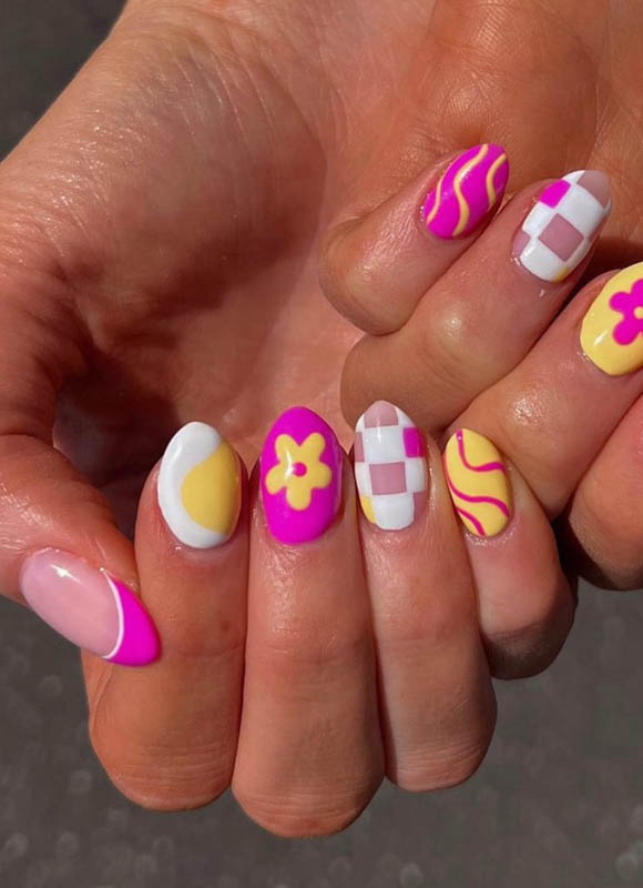 Two hands with colorful and creative nail art, including flowers, waves, and grids.

