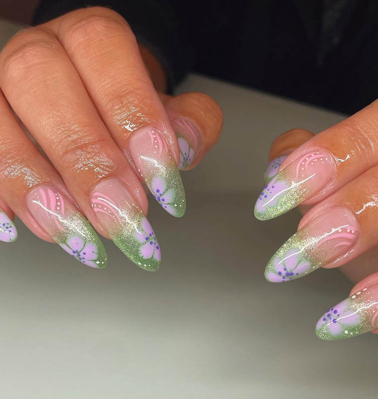 Spring Nail Designs For 2024. A close-up image of hands with pastel-colored nail art and floral patterns.

