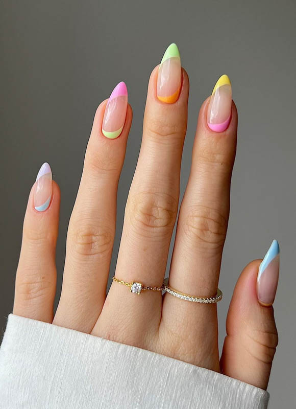 A hand with colorful gradient nails and rings on a grey background.
Spring Nail Ideas For 2024.