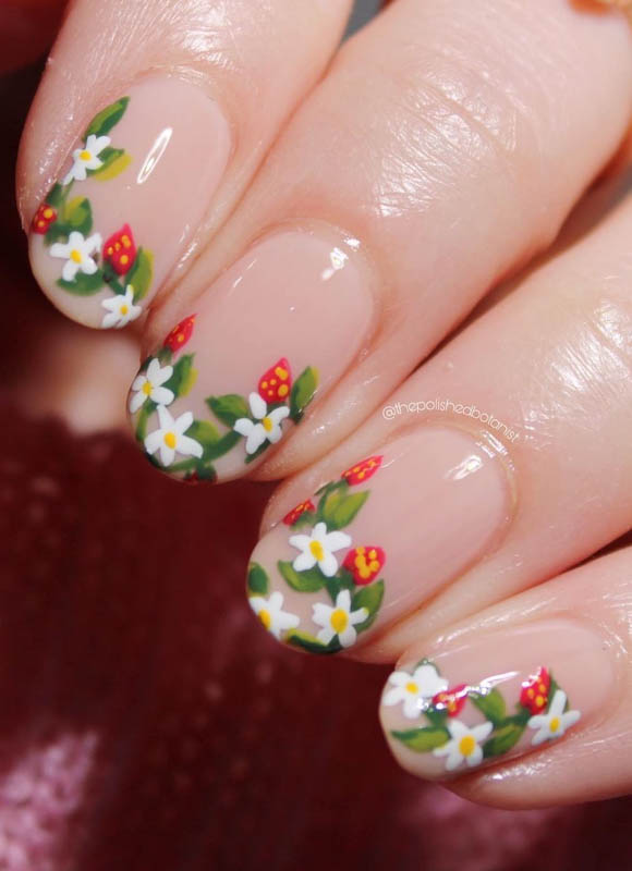 Spring Nail Designs For 2024. A close-up of nails with a clear polish adorned with detailed hand-painted flowers and strawberries.

