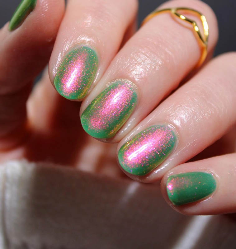 A close-up image of a hand with nails painted in a sparkling green and pink gradient nail polish, adorned with a gold ring on the ring finger.
Spring Nail Ideas For 2024.