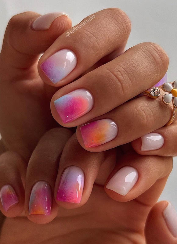 A close-up of two hands with pastel gradient nails and a gold ring. Spring Nail Ideas For 2024.