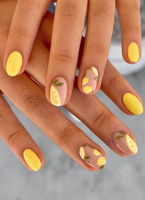 Spring Nail Ideas For 2024. Two hands with yellow polish and lemon slice nail art.

